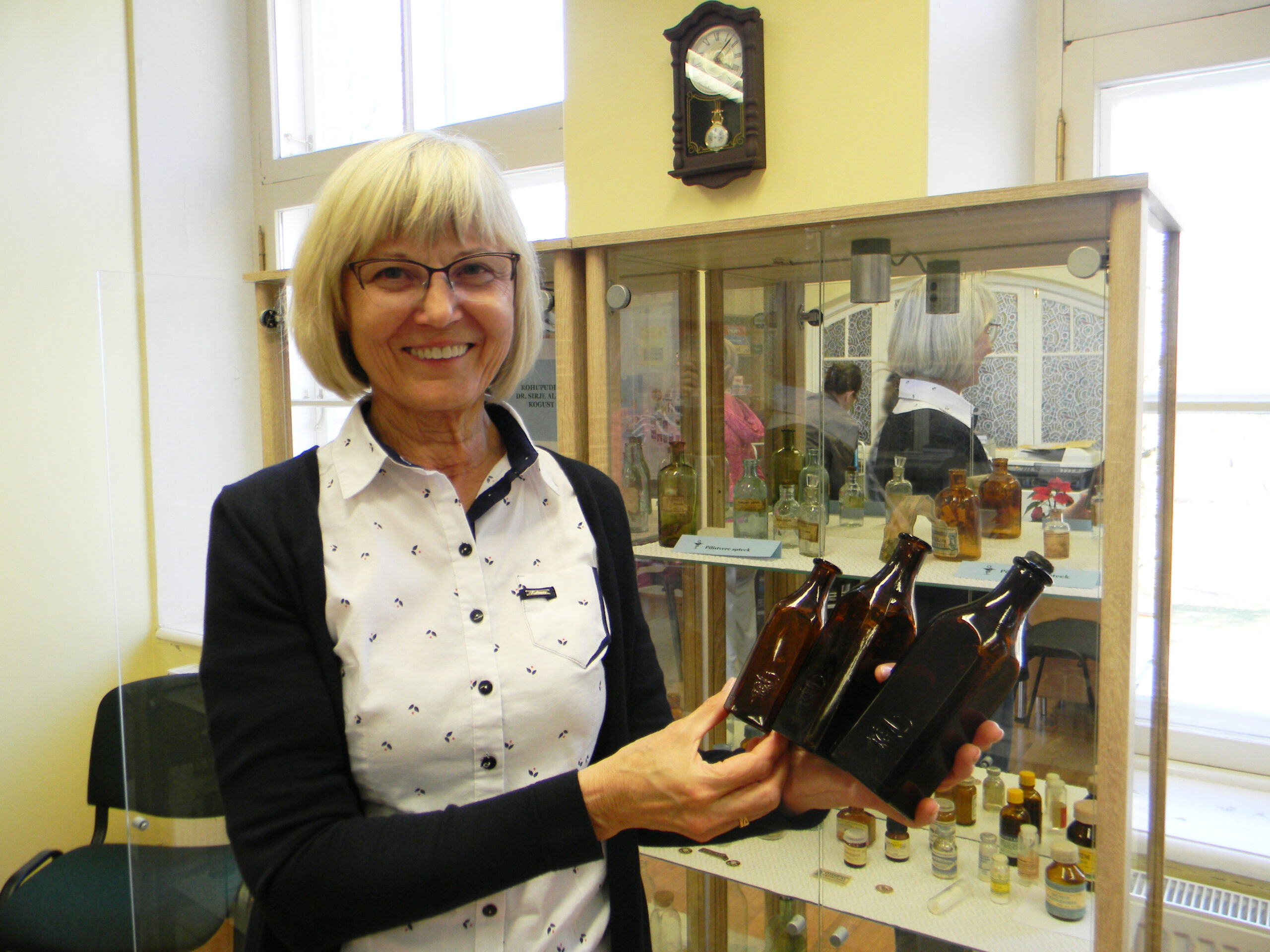 Dr Sirje Alusalu näitab Lorupi klaasivabrikus toodetud rohupudeleid, mida ehib mao ja karika märk. Foto Helis Rosin.